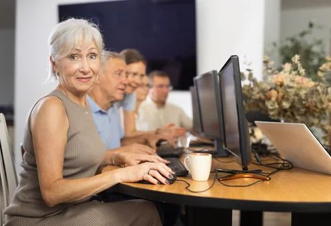 Old woman learning computer programs in training room Foto stock