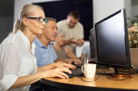 Old woman learning computer programs in training room Stock Photos