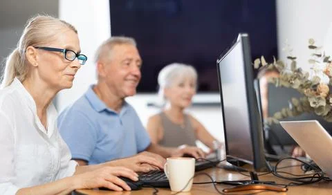Old woman learning computer programs in training room Foto stock