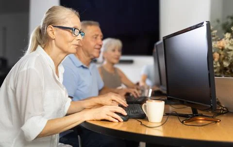 Old woman learning computer programs in training room Fotos de archivo