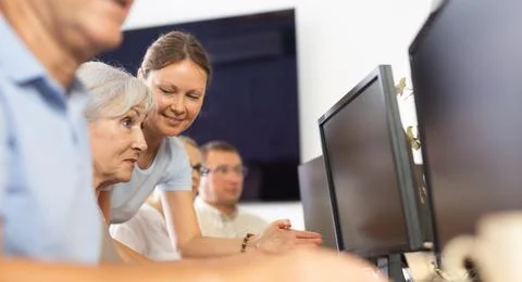 Old woman learning computer programs with teacher in training room 스톡 사진