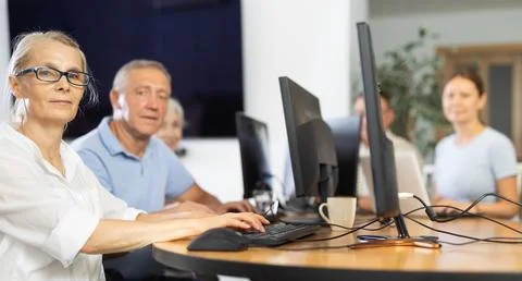 Old woman learning computer programs in training room Fotos de archivo