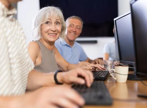 Old woman learning computer programs in training room Foto stock