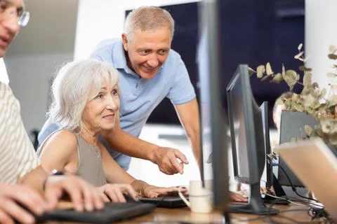Old woman learning computer programs with teacher in training room Stock-Fotos