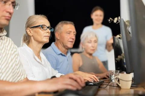 Old woman learning computer programs and teacher speaking on the background Stock Photos