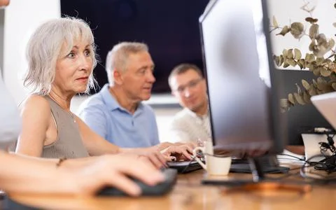 Old woman learning computer programs in training room Stock Photos