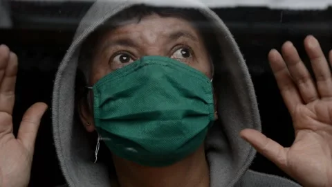 Old woman looking through the window with a face mask and hands up Stock Footage 133101485