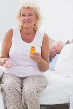 Old woman with an opened pill bottle Stock Photos