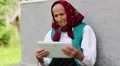 Old woman sits on bench and communicates via tablet computer HD Footage