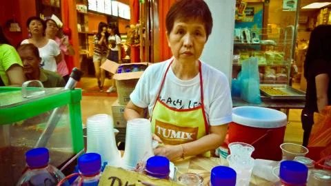 Old woman with a stack of plastic cups 库存照片