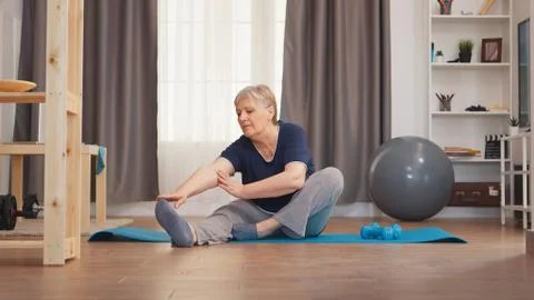 Old woman stretching on yoga mat Stock Photos