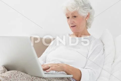 Old woman typing on her laptop Stock Photos