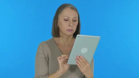 Old Woman Using Digital Tablet on Blue Background Vídeos de archivo 297055360