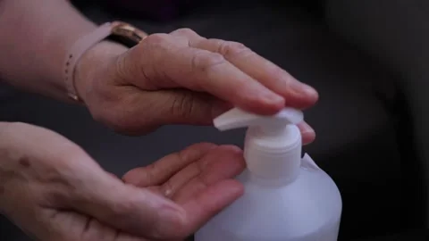 Old woman using hand sanitizer to kill viruses and stay safe Stock Footage
