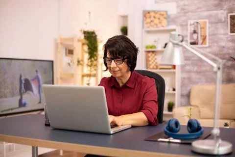 Old woman using a modern computer in her living room Foto stock