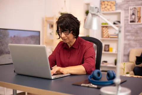 Old woman using a modern computer in her living room Foto stock