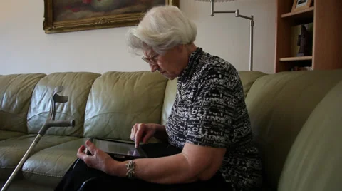 Old woman using a tablet computer on couch,disabled elderly female,sick,Internet Stock Footage 36544378