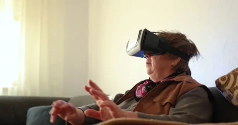 An old woman using Virtual reality headset. Handheld 4K Video Stockbeeldmateriaal 169180540