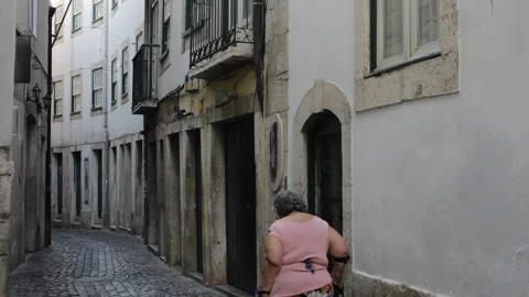 Old woman using walking stick walks in the narrow streets of Lisbon. Stock Footage 133582992