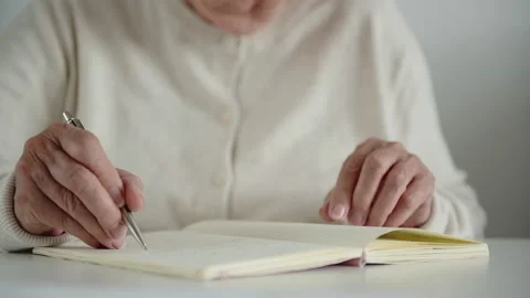 Old woman writes notes with trembling hand takes off glasses Stock Footage 164221966
