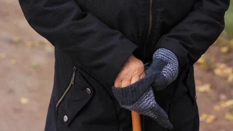 Old woman's hand puts on gloves and holds a cane for emphasis close up. Stock Footage 117781719