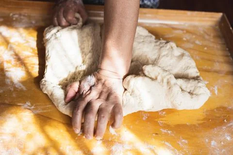 Old woman's hands kneading bread dough. Empanadas. Wooden table. Stock Photos