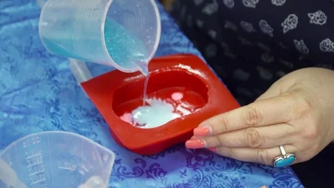 Old woman's hands pouring the soap base with sparkles to the template Stock Footage 74360428