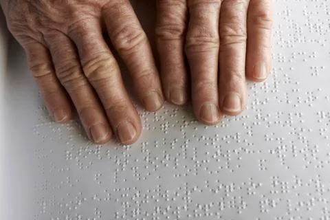 Old womans hands, reading a book with braille language Stock Photos
