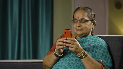Old women with eyeglasses using basic keypad mobile phone while at home - 스톡 동영상 198987972