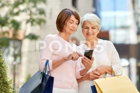Old women with shopping bags and cellphone in city Stock Photos