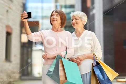 Old women with shopping bags taking selfie in city Stock Photos