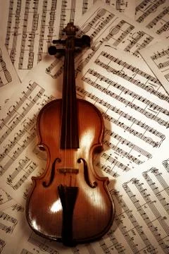 Old wood violin lying on musical notes Stock Photos