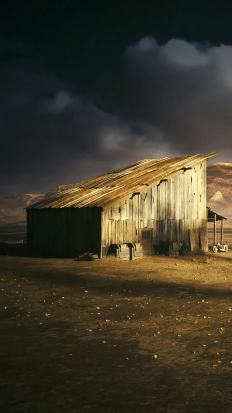 Old wooden barn stands alone in a dry field under a cloudy sky at dusk Stock Footage 339940683