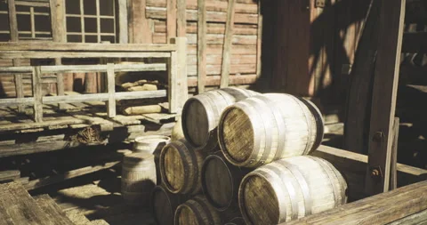 Old wooden barrels stacked in a rustic barn during daylight Stock Footage 341697122