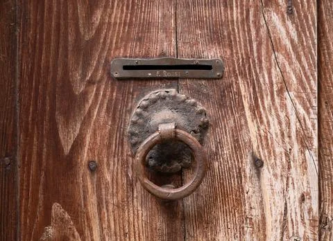 Old wooden door featuring rustic knocker and mail slot Stock Photos