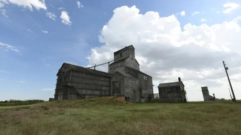 Old wooden grain elevator and farm buildings on the prairie with changing cloudy Stock Footage 163163093