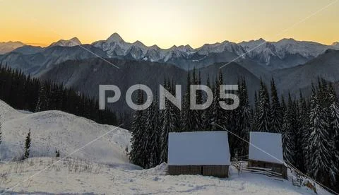 Old wooden house, hut and barn in deep snow on mountain valley, spruce forest Stock Photos