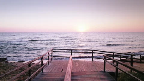 Old Wooden Steps on Long Beach at Sunrise: Waves Embracing the Sandy Shore in Stock Footage 329933036