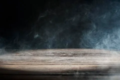 An old wooden table on a black background with smoke Stock-Fotos