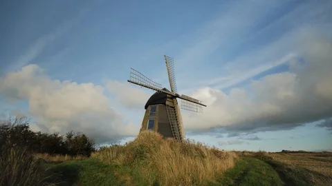 Old wooden windmill at a path with blue sky and light clouds. Parallax Stock Footage 117466249