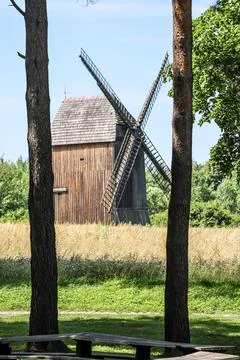 Old wooden windmill structure with large blades set against a sunny blue sky Stock Photos