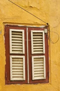 An old wooden window with closed shutters in a yellow painted brick wall Stock Photos