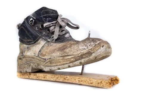 An old work boot with a nail. Construction worker's damaged work clothes. Stock Photos