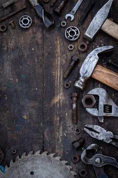 Old work tools nuts, bolts and bearings lie on a wooden workbench Stock Photos