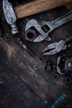 Old work tools nuts, bolts and bearings lie on a wooden workbench Stock Photos