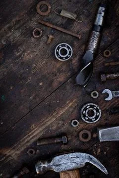 Old work tools nuts, bolts and bearings lie on a wooden workbench Stock Photos