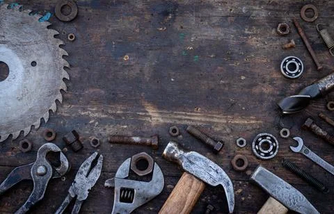 Old work tools nuts, bolts and bearings lie on a wooden workbench Stock Photos