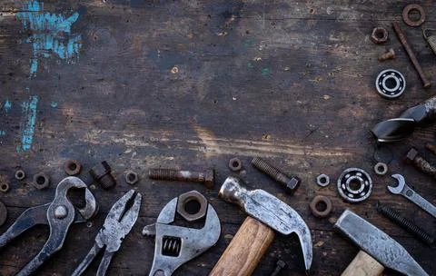 Old work tools nuts, bolts and bearings lie on a wooden workbench Stock Photos