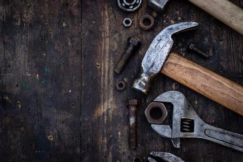 Old work tools nuts, bolts and bearings lie on a wooden workbench Stock Photos