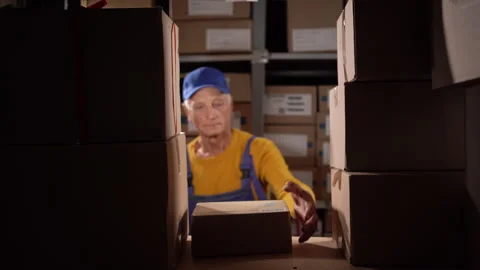 Old worker working in storage, taking parcel and scanning barcode, putting box 스톡 동영상 248665031
